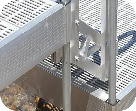 Close-up of a metal dock ladder attached to an Aluminum Docks grated platform above water, showing structure and connection details.