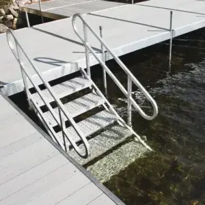 Metal stairs with handrails lead from a wooden dock into clear, shallow water, with Great Northern Docks’ expert craftsmanship visible in the background.
