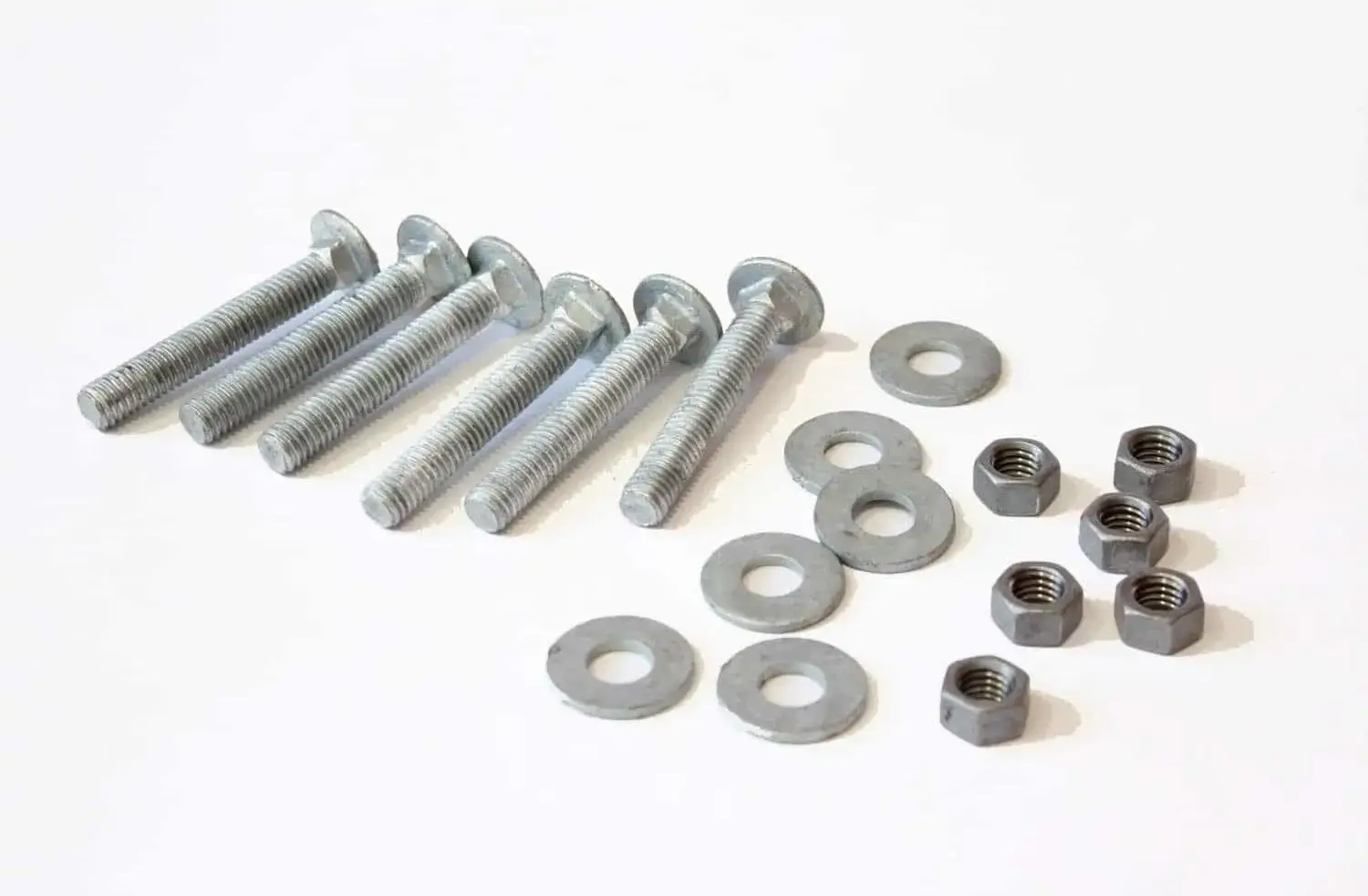 Six bolts, six washers, and six hex nuts from the Galvanized Carriage Bolt Attachment Kit are arranged neatly on a white surface.