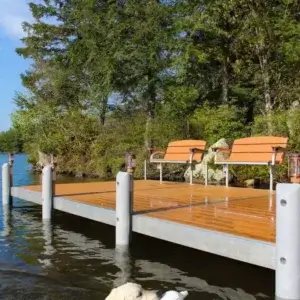 A dog swims in a lake with a toy near a Fixed Dock on Legs with two benches, surrounded by trees and blue sky.