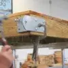 A person uses a hammer on a Reinforced Hinge Plate attached to wood, stabilized by locking pliers—a technique common at Maine docks by Great Northern Docks.