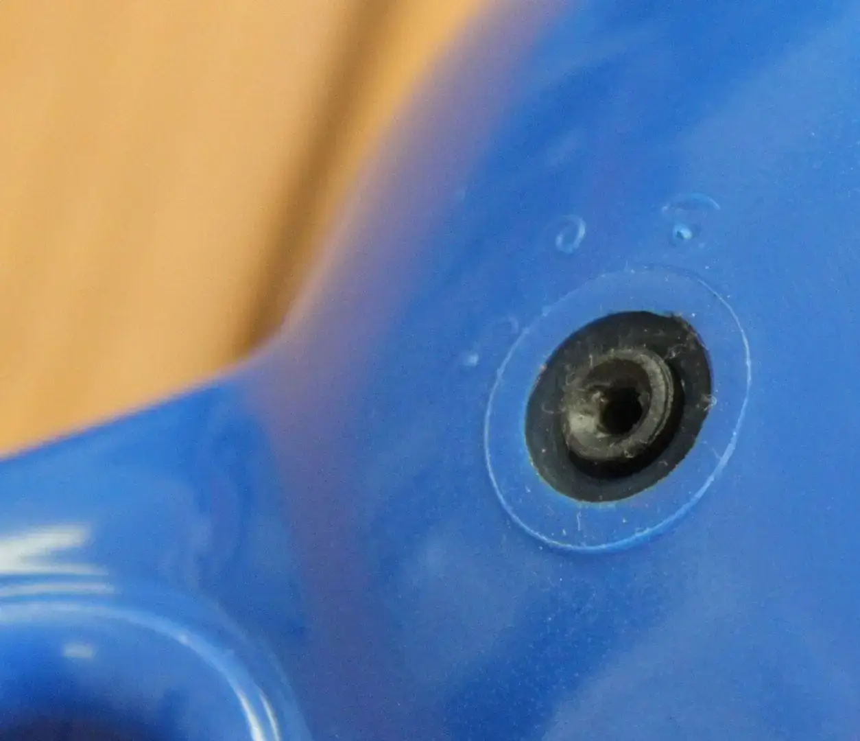 Close-up of a blue "Boat Bumpers (Inflatable)" from Great Northern Docks, with a small black hole and two raised dots; tan background blurred.