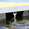 Close-up of an Anchor Plate Keyhole from Great Northern Docks attached under a floating dock frame, with metal chain and water reflections visible.