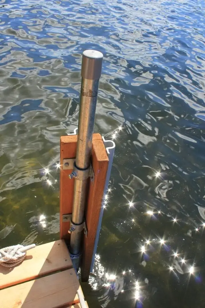 A close-up of a Corner Rail Bracket from Great Northern Docks attached to wooden planks, with sunlight reflecting off the water in the background.