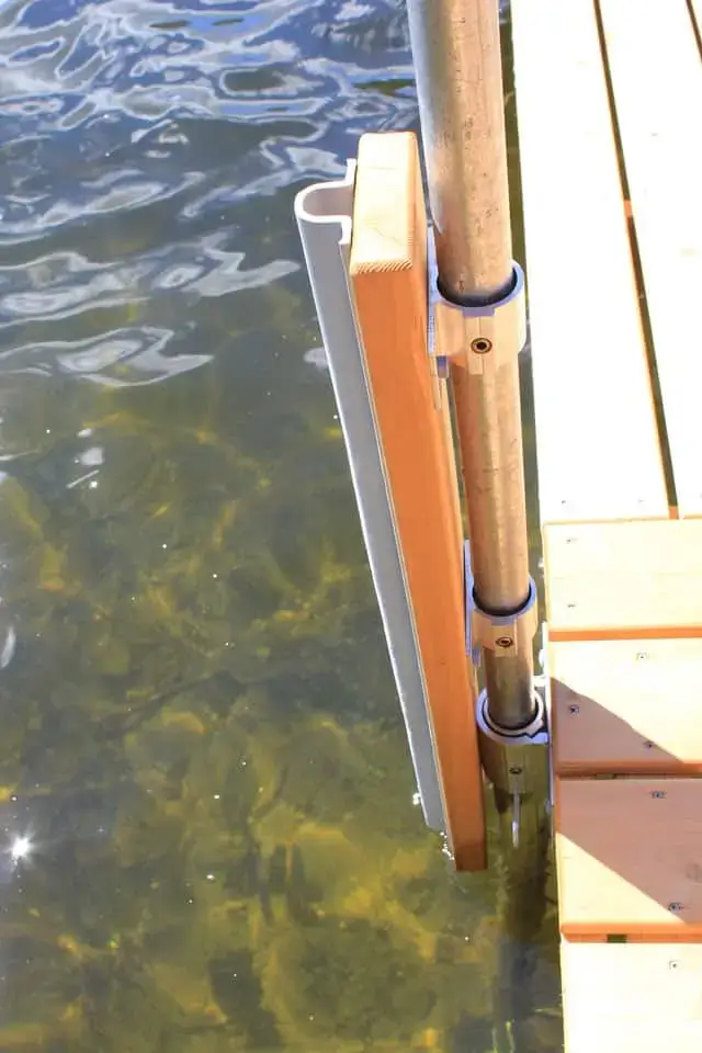 A close-up of a Great Northern Docks edge featuring Rail Brackets and metal poles, stretching into clear water with visible rocks below.