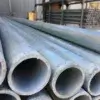 Close-up of stacked 1.5" Sch. 40 Galvanized Pipe arranged horizontally, with Great Northern Docks shelves and more pipes blurred in the background.