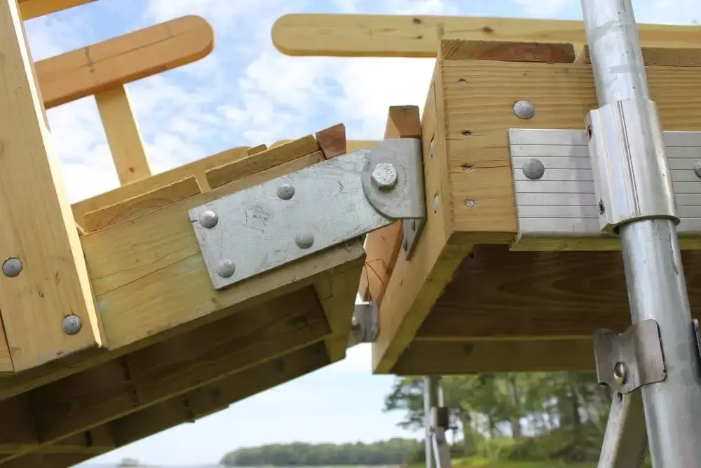 Close-up of a Reinforced Hinge Plate on a wooden structure outdoors, with trees and blue sky in the background, typical of Great Northern Docks.