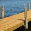 Wooden dock with metal posts from Great Northern Docks extending over calm blue water on a sunny day.