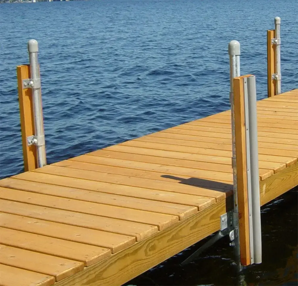 Wooden dock with metal posts from Great Northern Docks extending over calm blue water on a sunny day.