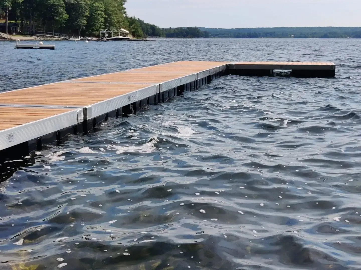 A Floating Dock from Great Northern Docks stretches over the lake, with trees and boats in the background beneath a cloudy sky.