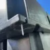 A screw is lodged in the bottom corner of a stacked black Dock Float Attachment Kit (Foam Filled) from Great Northern Docks, with clear blue sky behind.