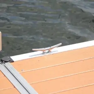 An Aluminum Cleat 8" is installed on a light brown wooden dock by calm water, illustrating the quality of Great Northern Docks.