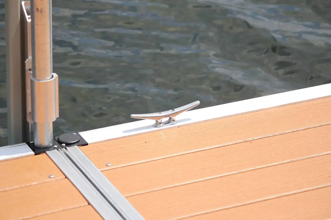 An Aluminum Cleat 8" is installed on a light brown wooden dock by calm water, illustrating the quality of Great Northern Docks.