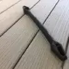 A black Mooring Snubber with a handle and two rectangular openings lies diagonally on light gray composite deck boards from Great Northern Docks.