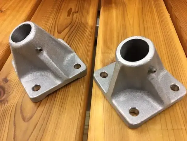 Two Mooring Whip (2 Pack) brackets with angled cone-shaped mounts and four screw holes each, great for securing wood or aluminum docks, shown on a wooden surface.