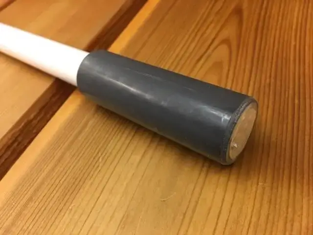 A close-up of a Mooring Whip (2 Pack) with a white handle and gray rubber cap, resting on wood near Great Northern Docks.