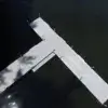 Aerial view of Boarding Steps from Great Northern Docks, a T-shaped aluminum dock over dark water with sunlight and tree shadows on the surface.