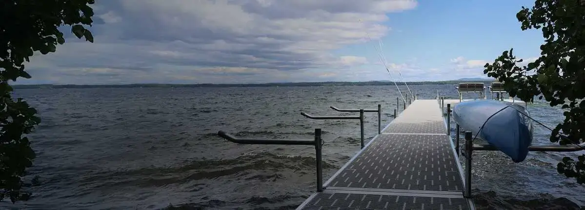A blue canoe is stored on docks over a lake under a cloudy sky.