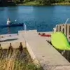 kayak_rack-03-low A man paddles a blue kayak on a lake near a Connect-A-Dock, which holds a green kayak, shoes, a red life vest, and a yellow-flower planter.